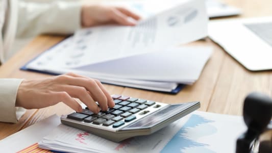 Une personne regarde un document avec une calculatrice.