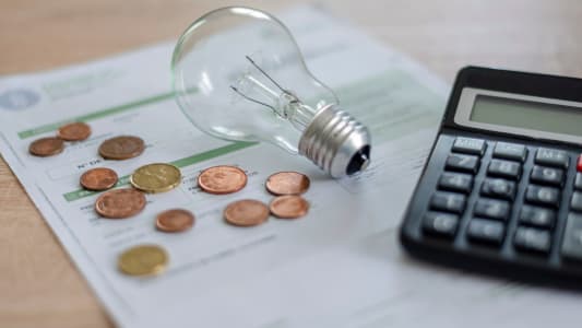 Une calculatrice, une ampoule, des pices de monnaie et une facture.