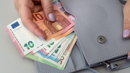 Quelqu'un range des billets dans un portefeuille.