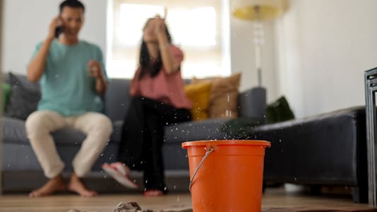 Un homme et une femme au tlphone aprs un dgts des eaux dans leur logement.