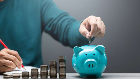 Quelqu'un met de l'argent dans une tirelire.