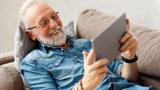 Une personne regarde une tablette en souriant.