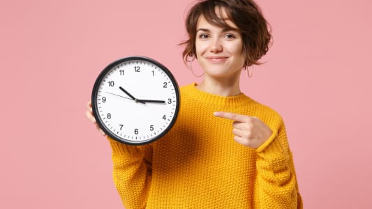 Une femme dsigne une horloge.