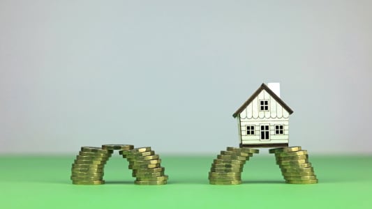Deux piles de pices qui se rejoignent et une maison miniature.