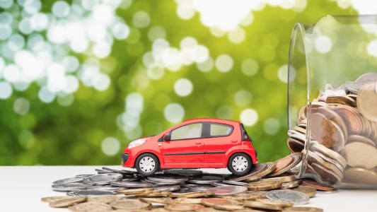 Une voiture miniature roule sur des pices de monnaie.