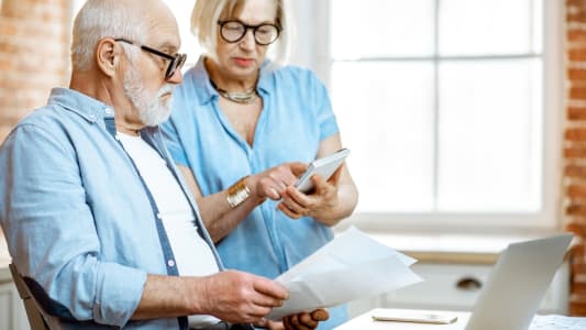 Un homme et une femme regardent des documents et une calculatrice