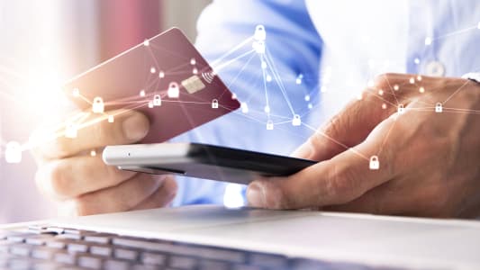 Une personne regarde une carte bancaire et son téléphone.