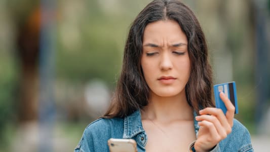 Une femme regarde sa carte bancaire et son tlphone.