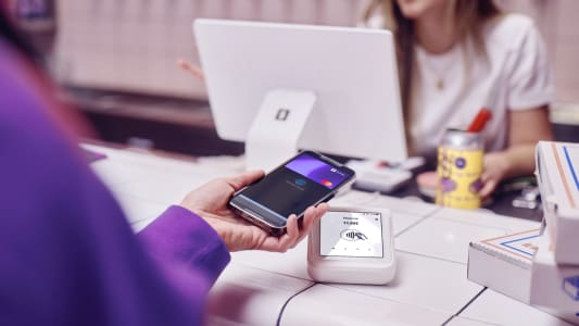 Une personne tend son tlphone pour payer.