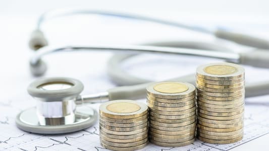 Des piles de pices de monnaie et un stthoscope.