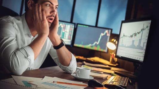 Un homme regarde des indicateurs boursiers l'air inquiet.