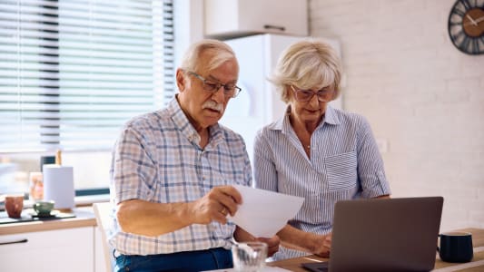 Un couple de personnes ges regardant un ordinateur.