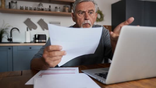 Un homme l'air choqu devant son ordinateur.
