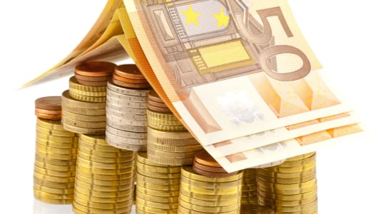 Une pile de pièces et des billets, en forme de maison.