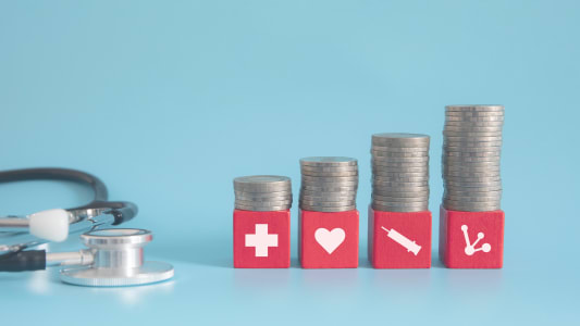 Des piles de pices de monnaie et un stthoscope.
