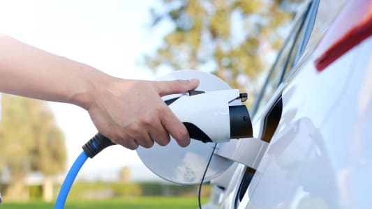 Une personne recharge une voiture électrique.