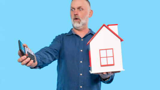 Un homme regarde une calculatrice l'air surpris. 