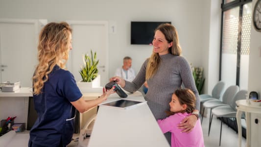 Une femme avec un enfant rgle une consultation chez un mdecin.