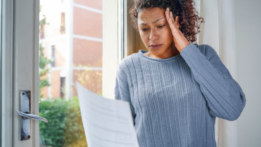 Une femme regarde un document en se tenant la tte.