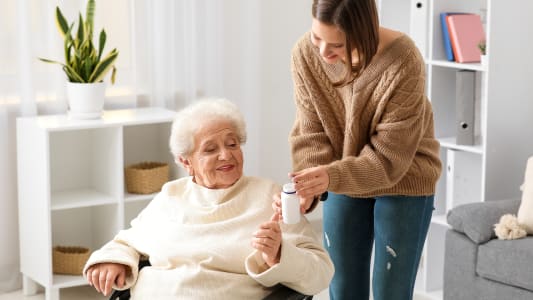 Une femme aide une personne âgée.