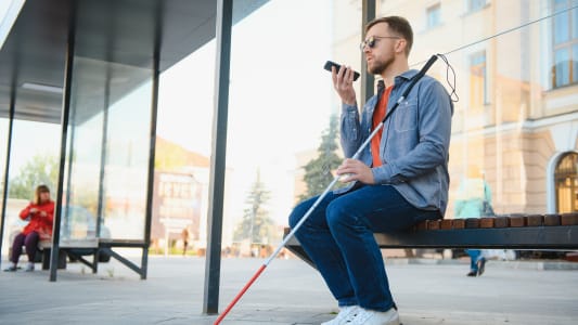 Un homme non voyant à un arrêt de bus.