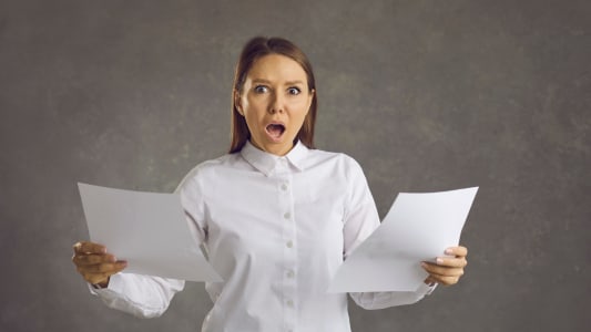 Une femme regarde des documents l'air surpris.