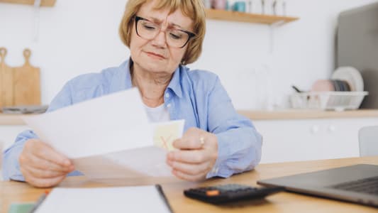 Une femme regarde un document avec une calculatrice.