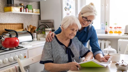 Deux personnes regardent des documents dans une cuisine.