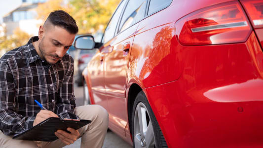 Un homme crit dans un carnet prs d'une voiture