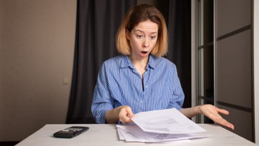 Une femme regarde un document l'air surpris.