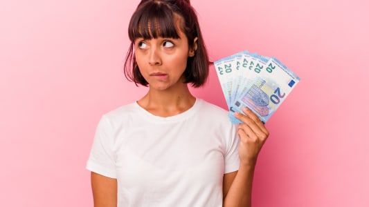 Une femme s'interroge avec de l'argent dans la main.
