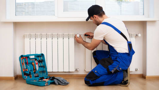 Un homme installe un thermostat sur un radiateur