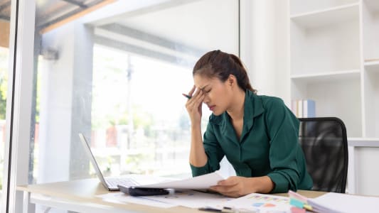 Une femme se tient la tte  son bureau.