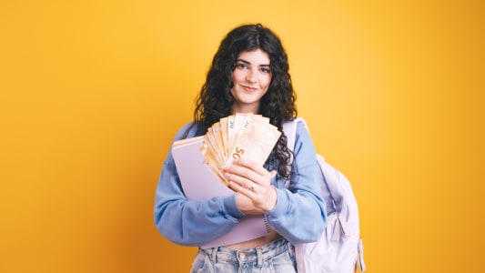 Une femme avec un sac  dos tient plusieurs billets de 50 euros.