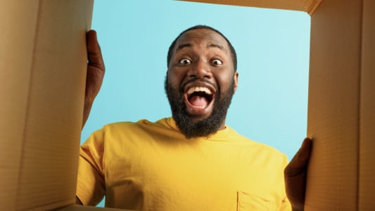 Homme surpris regardant  l'intrieur d'une bote en carton.