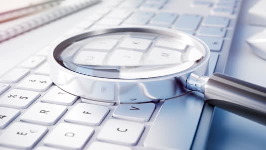 Loupe pose sur un clavier d'ordinateur, recherche de dtails.