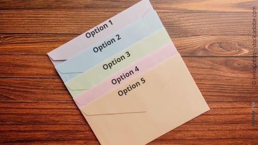 Enveloppes colorées numérotées sur une table en bois.