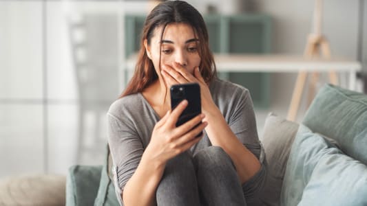 Une femme lisant de mauvaises nouvelles sur son smartphone, se sentant triste et inquite.