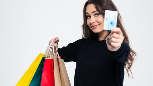 Femme heureuse tenant des sacs de shopping et une carte bancaire