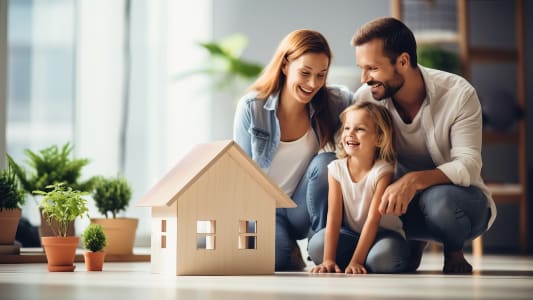 Famille souriante regarde une maison mod�le � l'int�rieur.