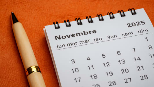 Calendrier de novembre 2025 avec un stylo sur fond orange.