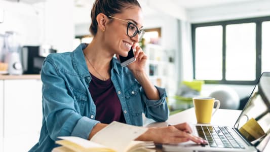 Une femme souriante travaillant avec un ordinateur portable.