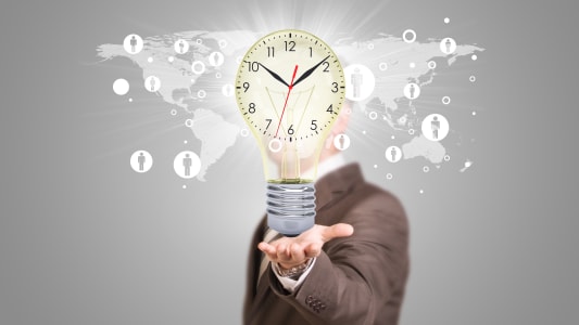 Un homme d'affaires en costume tient une ampoule avec une horloge