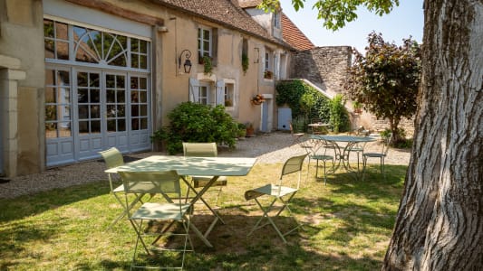 Cour intrieure avec tables vertes devant maison traditionnelle franaise.