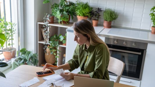 Une femme calculant les factures d'lectricit sur la calculatrice de son smartphone.