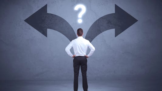 Homme d'affaires prenant une dcision tout en regardant les flches sur le mur comme concept