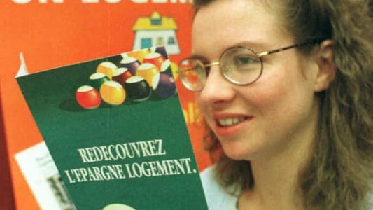 Femme souriante tenant une brochure sur l'épargne logement.