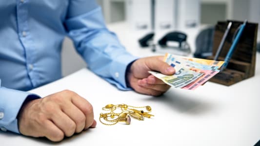 Un homme tendant une somme d'argent en change de bijoux en or