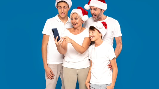 Famille joyeuse avec bonnets de Nol regardant un smartphone.