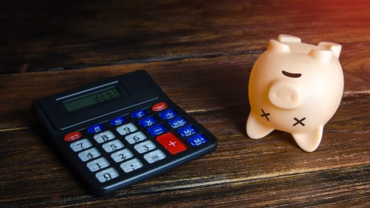 Calculatrice et tirelire sur fond en bois.